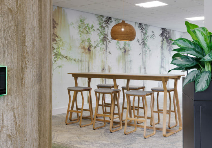Wooden high table and high stools in green office space